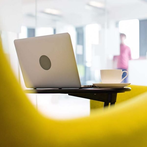 Laptop and coffee cup on table in office