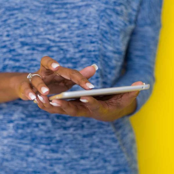 Young Happy African American Woman Using Digital Tablet Isolated on a yellow background