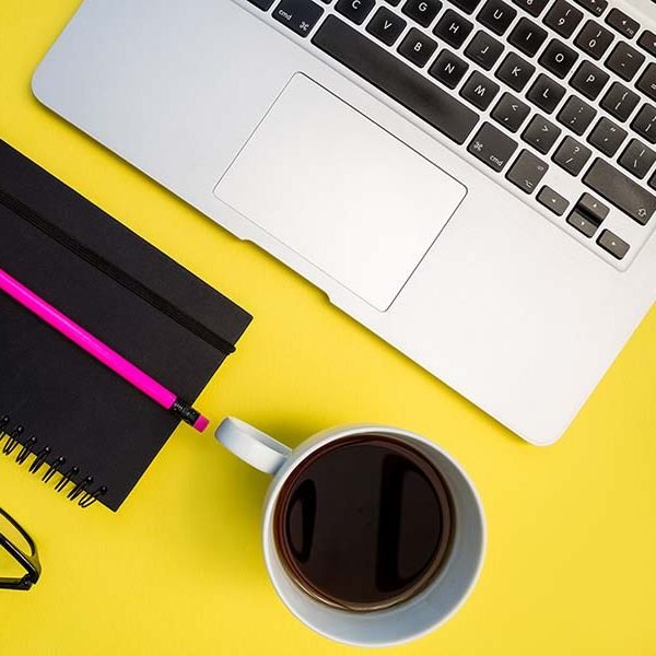 Laptop computer notebook eyeglasses on bright yellow background